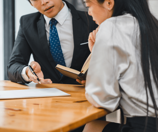 Two professionals discussing documents at a wooden table.