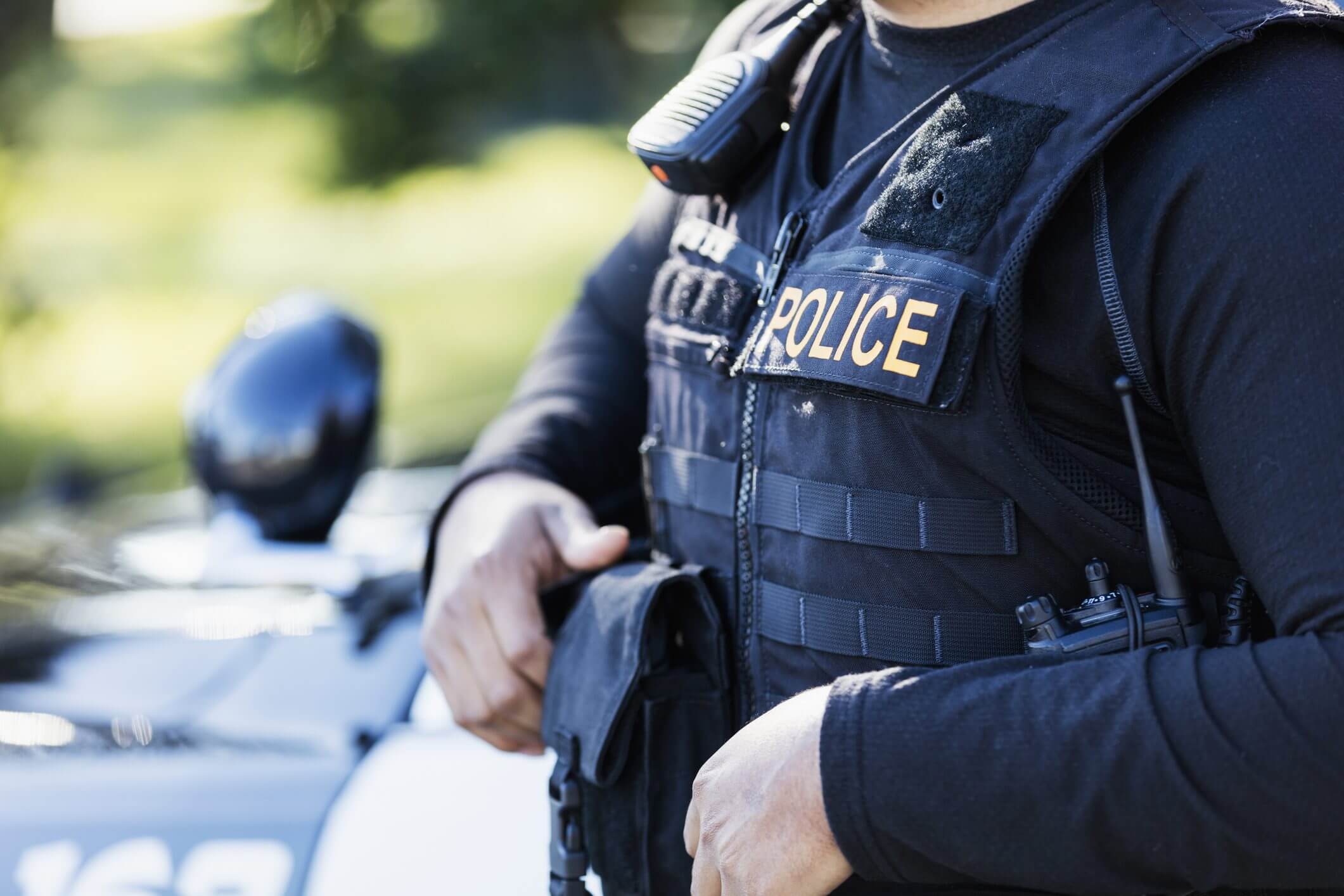 Police officer in tactical gear standing by a motorcycle.