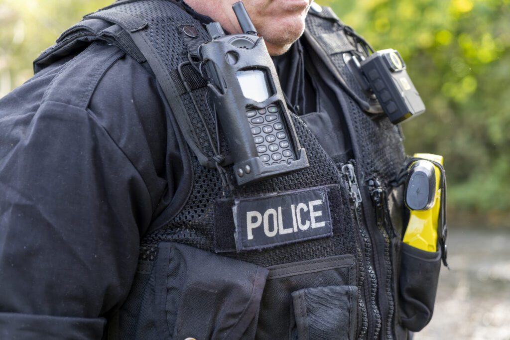 Close-up of a police officer wearing tactical gear and communication devices.