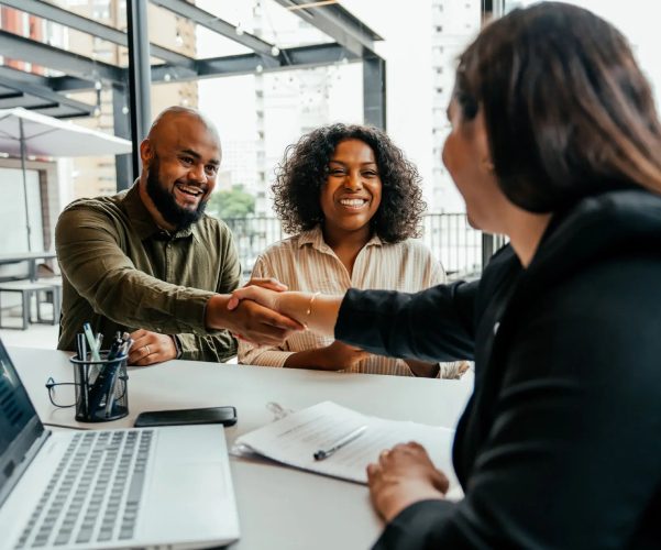Two people shaking hands with a professional at a meeting.