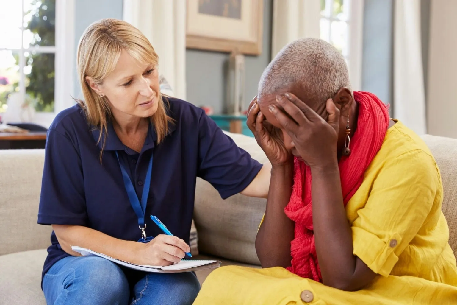 Counselor comforting a distressed woman on sofa.