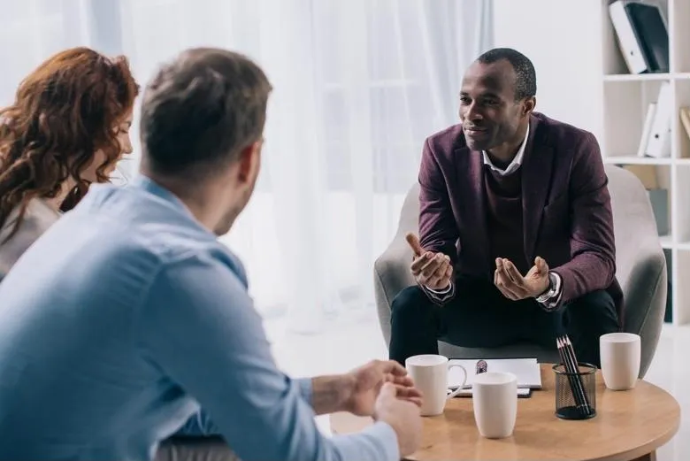 Three people having a discussion over coffee.
